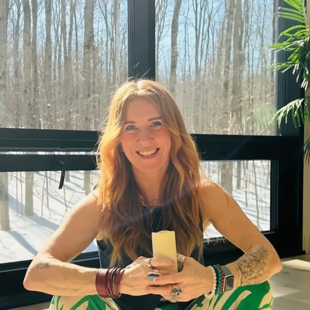 Michelle smiling, holding a candle by a sunlit window
