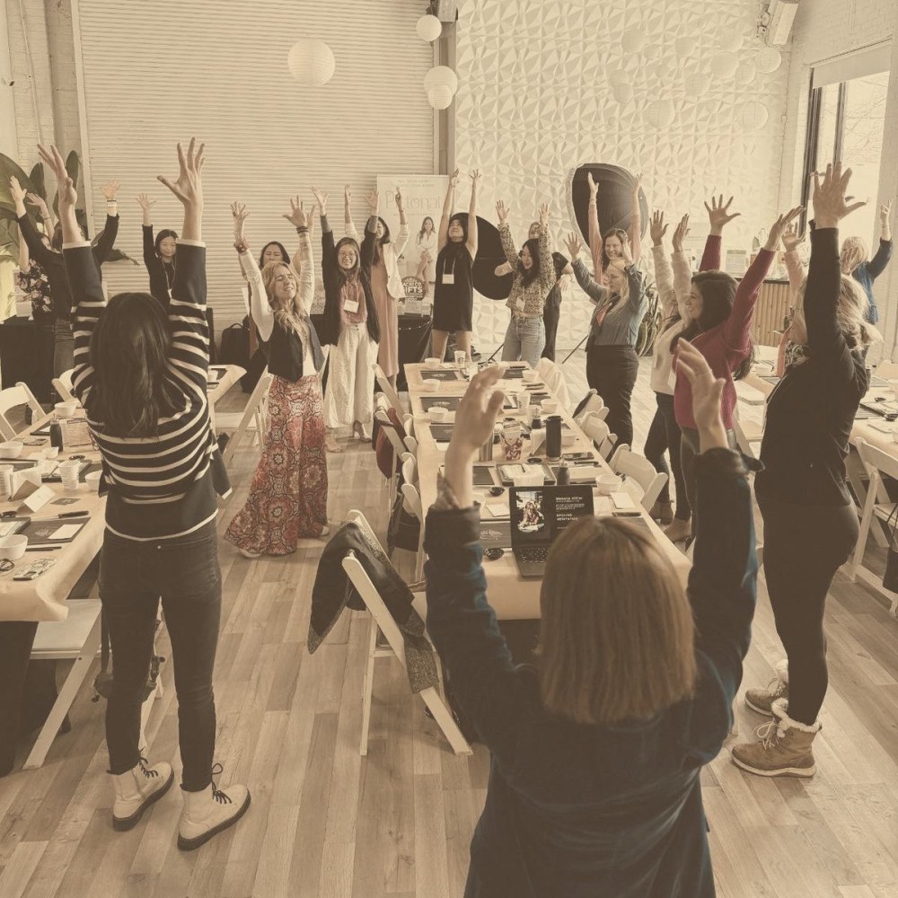 A full room on its feet, arms raised, in one of Michelle's sessions
