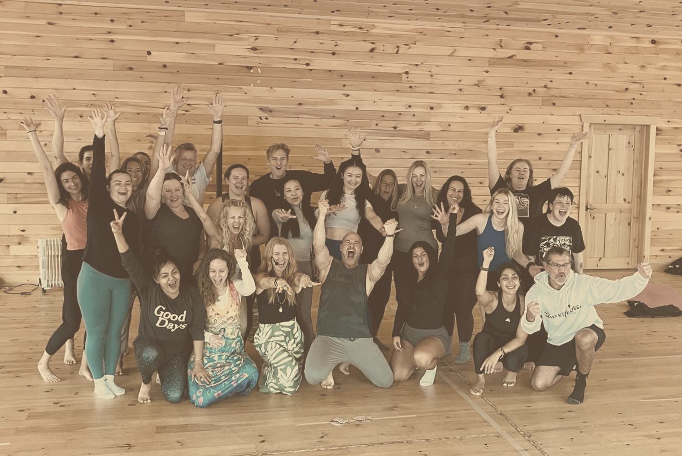 A group celebrating together with arms raised in a wooden studio